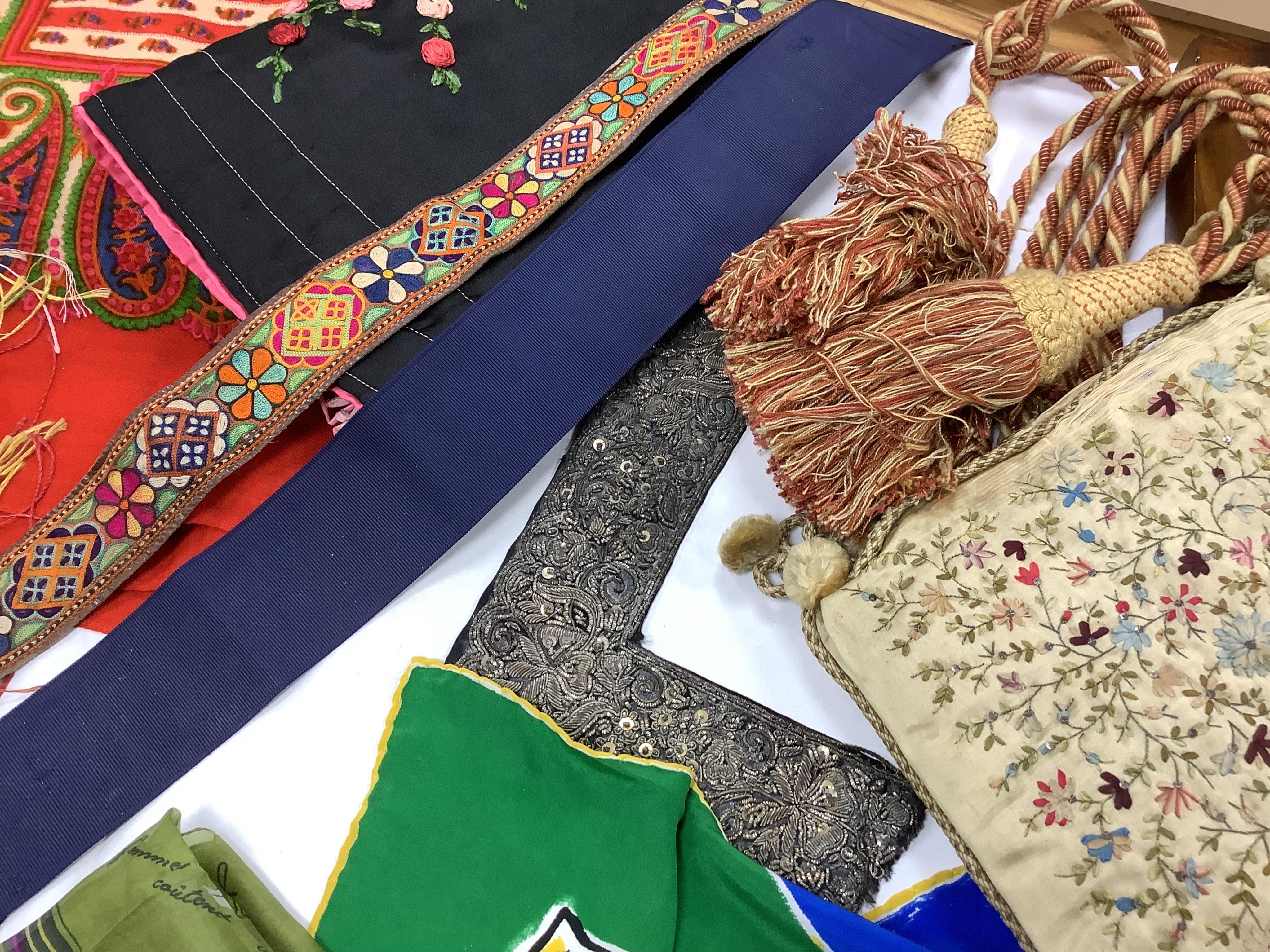 A collection of textiles: a ribbon work hankie and pyjama case, a metalwork collar, a coloured printed shawl, a nurses belt and embroidered belt, an advertising Guggenheim Bilbau hankie etc (10). Hankie case 22cm square.